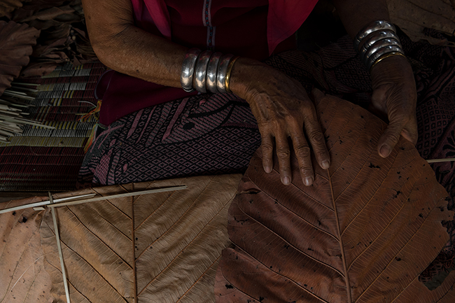 The wrinkles of 58-year-old Mu La's skilled hands are like the lines of the teak leaves she weaves into bamboo sticks.