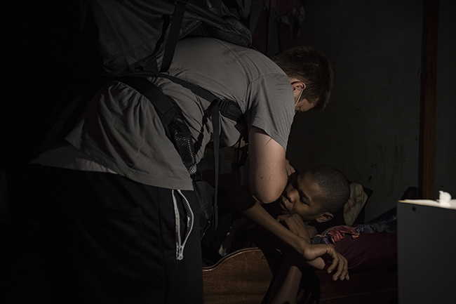 In a house without electricity, Clément, a private nurse in Mayotte, administers an insulin shot to his patient using the light from his mobile phone. Mayotte - 2021