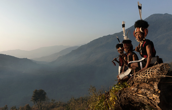 Khiamniungan Naga warriors seated in the front of misty mountains.