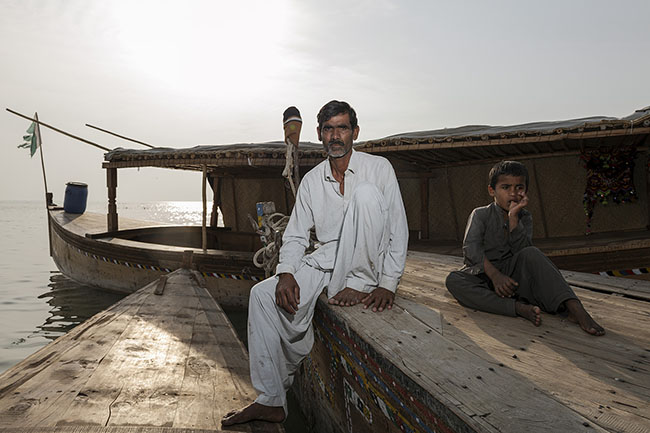 Aziz, seated on the prow of a Mohana boat. The Galiyo — flat-bottomed wooden barges, delicately crafted — are the legacy of this people also known as Mallah (the name of their boatmen caste) or Mirbahar, literally “lords of the sea”.