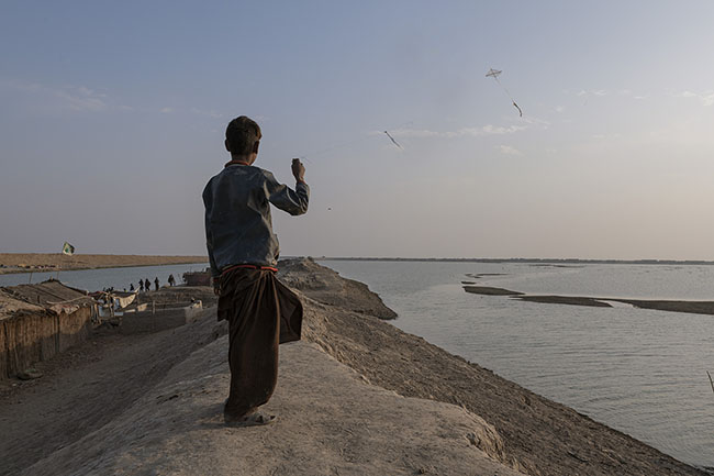 A Mohana child flies his kite above Lake Manchar. Despite the difficulties, the gestures of childhood persist, light and fleeting like the wind.