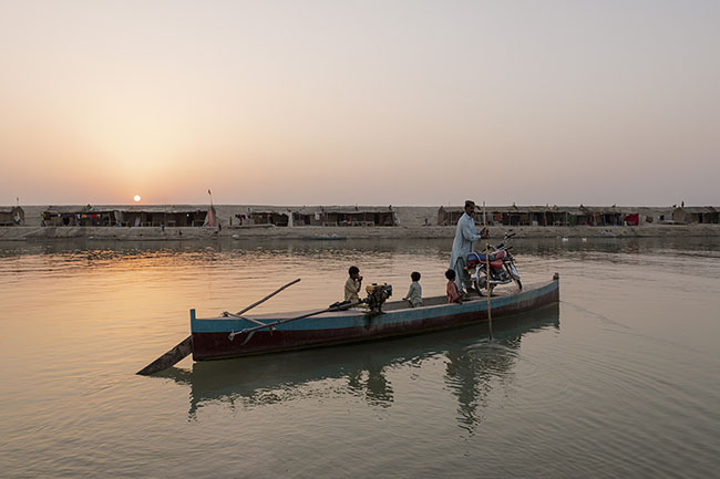 Ali ferries the children and the community’s motorcycle across with his boat. This two-wheeled vehicle is their only link to the outside: a bridge between their isolation and the outside world.