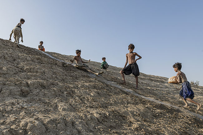 Improvised slide on the steep slope of the Right Bank Outfall Drain (RBOD) bank. The gestures of childhood persist: they slide carefreely. The source of their misfortune turned into a playground.