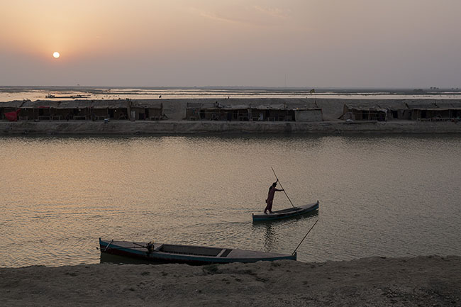 Propelled by a long bamboo pole scraping the muddy bottom of the canal, Bashir maneuvers his boat with precision. Each gesture carries the memory of the Mohana people. In front of him, the reed huts on the shore already seem like ruins. And as the sun sets behind the horizon, he continues to believe: perhaps a breath, a trace, a memory will survive.