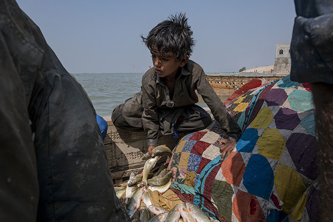A Mohana child helps his father return from fishing.