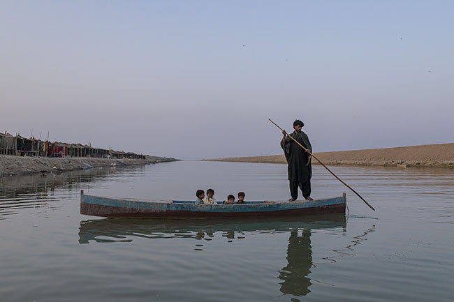 Mohamed ferries children from one bank to the other of the Right Bank Outfall Drain (RBOD) in his boat.