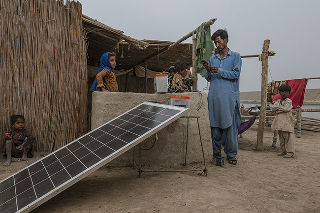 Bashir tries to charge his mobile phone on the only source of electricity in the camp: a solar panel connected to a few batteries. Like potable water, access to electricity is a precarious luxury for the Mohanas. The phone is often their only link to the outside world.