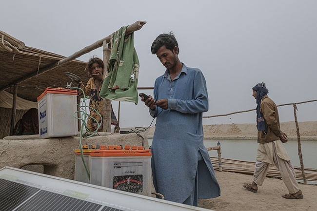 Bashir tries to charge his mobile phone on the only source of electricity in the camp: a solar panel connected to a few batteries. Like potable water, access to electricity is a precarious luxury for the Mohanas. The phone is often their only link to the outside world.