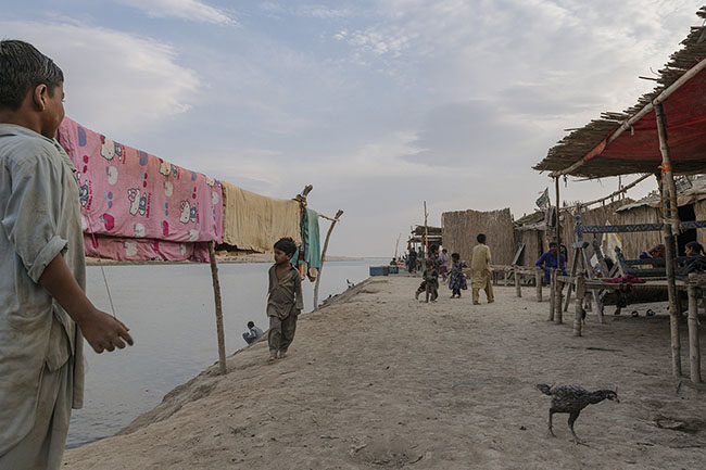 Along the brackish waters of the RBOD, children walk barefoot in the dust in front of a row of huts made from tarps, reeds, and salvaged materials. When it’s hot, the Mohanas sleep outside in the dust, and when the rain comes, they seek refuge inside, but the water seeps in, and the mud takes over everything.