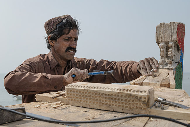 A Mohana boatman repairs a Galiyo, the iconic floating home of his community.