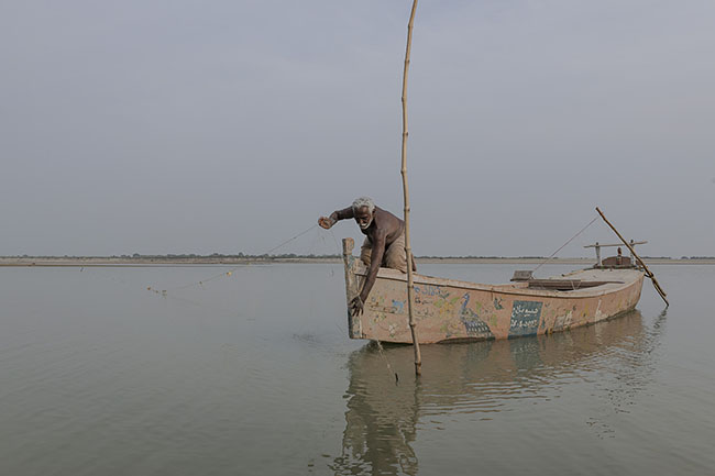 Yusuf, 58, a Mohana fisherman, casts his nets in the waters of the Indus River. Once settled by Lake Manchar, he now lives in a small village where he has resettled with his family.